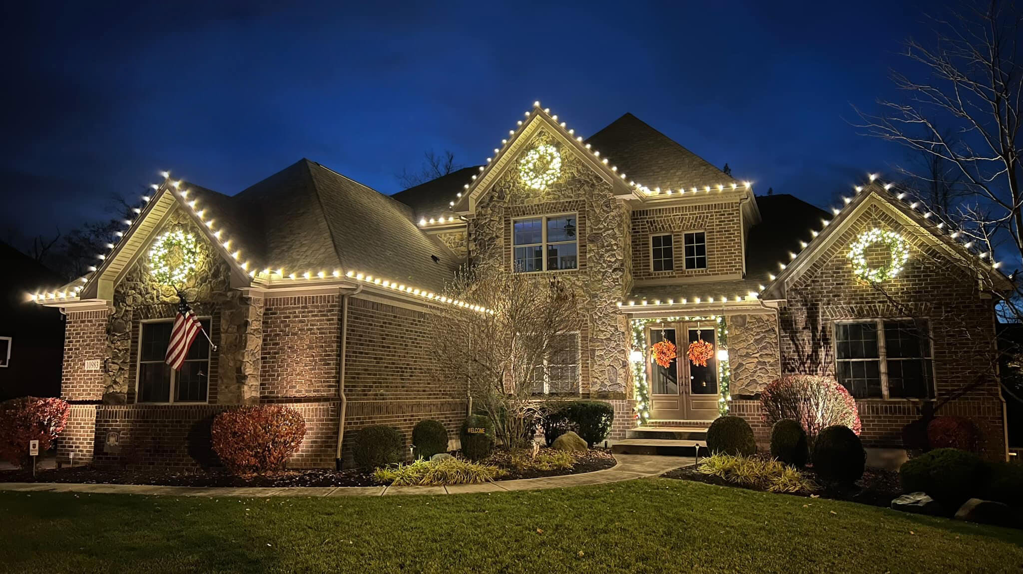 Elegant roofline Christmas lights and wreaths on a brick home